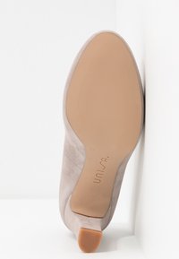 Chaussure à talon avec une tige en suède gris clair, un bout pointu et une semelle en caoutchouc beige lisse. Comprend un talon léger et un logo embossé. Taille 37.