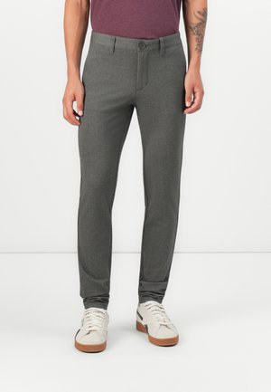 Pantalones gris ajustados con una textura suave, que cuentan con un bolsillo frontal, cierre de botón y combinados con zapatillas blancas.