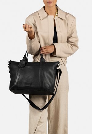 Schwarze Ledertasche mit strukturiertem Finish, doppelten Griffen und verstellbarem Schultergurt. Enthält ein markantes Anhängerdetail und minimale Nähte.