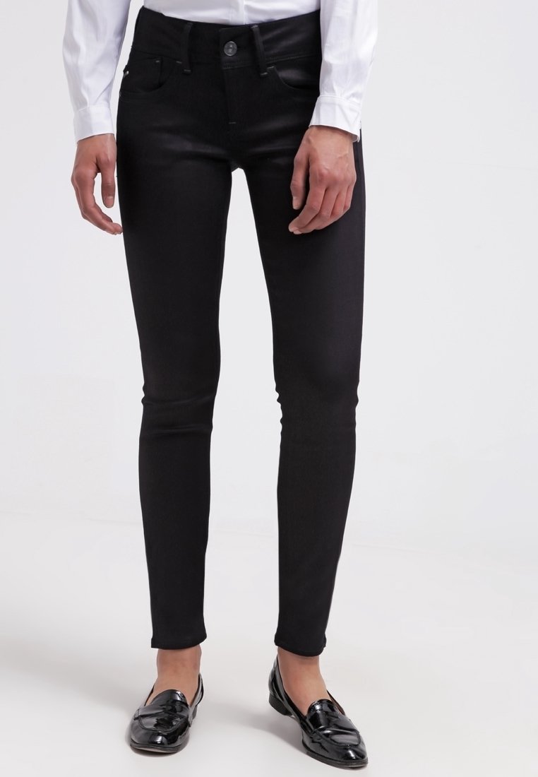 Vaqueros negros ajustados de denim elástico, con una cintura de altura media, diseño de cinco bolsillos y una textura suave y atractiva.