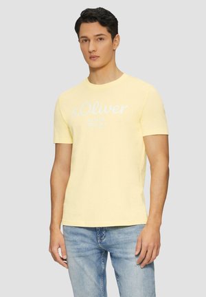 Camiseta de algodón amarilla con mangas cortas, que presenta una impresión de logo blanco que dice "s.Oliver Elevated Essentials" en el frente.