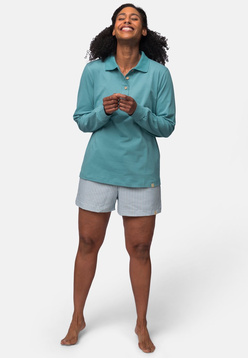 Teal langärmliges Poloshirt mit Knopfleiste und hellblauen gestreiften Shorts; lässige Passform, weiches Baumwollmaterial, barfuß.