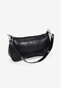 Bolso de mano de cuero negro con una textura suave, forma curva, cierre con cremallera y acentos de metal plateado. Las correas se sujetan con anillos circulares.