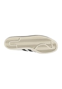 Suola di scarpa da ginnastica bianca con strisce nere, materiale in gomma, motivo strutturato per la presa e suola esterna in gomma color crema a contrasto.