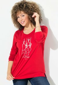Rode langemouw shirt van zacht materiaal met witte grafische prints met een feestelijk thema, waaronder bellen en versieringen, in een comfortabele pasvorm.