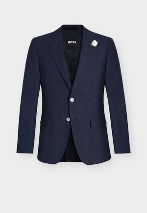 Marineblauw getailleerd colbert met inkeping revers, twee-knops sluiting, klepzakken, zwarte voering en witte reversbloemspeld.