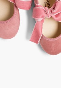 Ballerines en suede rose avec un bout rond, ornées d'un large nœud en velours à la cheville et d'une doublure intérieure lisse.