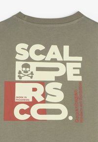 Camiseta de algodón verde oliva con un llamativo texto gráfico en blanco y rojo, que incluye un diseño de calavera y huesos cruzados, con la inscripción "Exposición de Arte Moderno de Copenhague".