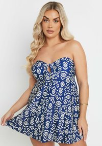 Vestido azul sin tirantes con un lazo en la parte delantera, que presenta un patrón geométrico blanco, falda acampanada y textura de tela suave.
