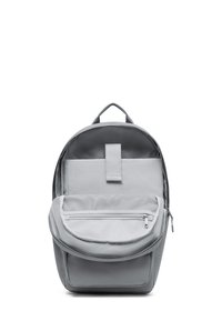 Grå tygryggsäck med rundad form, ett handtag upptill, framficka med dragkedja och mesh-detaljer. Slät textur med minimal design.