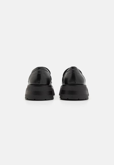 Pereche de loafers din piele neagră, cu platformă, văzuți din spate, cu tălpi groase și "Chiara Ferragni" embosat pe toc.