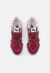 Červené semišové tenisky s bílými kostkovanými akcenty, dvojitými suchými zipy a bílými gumovými podrážkami s vyztuženými špičkami a prošívanými detaily.