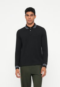 Melnas garām piedurknēm polo krekls ar apkakli, ar baltām svītrām apkaklē un piedurknēs, ar izšūtu logotipu uz krūškurvja.