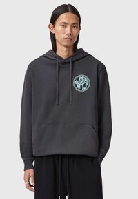 Felpa nera con cappuccio e tasca frontale, caratterizzata da un logo circolare azzurro chiaro sul petto. Tessuto morbido e vestibilità rilassata.