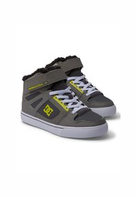 Zapatillas altas en gris y negro con un collar peludo, acentos amarillos, cordones blancos y una suela de goma con un logotipo en el lateral.