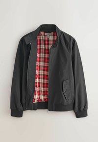 Melnā jaka ar rāvējslēdzēja priekšpusi, ribotas aproces un sānu kabatu ar sarkanas, baltas un melnas rūtainas oderes izskatu. Gluda ārējā tekstūra.