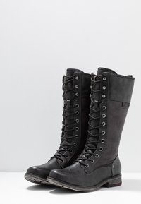 Stivali alti in pelle nera e suede, con lacci sulla parte anteriore, punta rotonda e tacco impilato. Presentano grommets metallici e dettagli testurizzati.