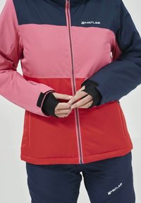 Giacca tricolore in rosa, rosso e blu navy. Presenta una chiusura lampo completa, colletto rialzato e polsini elasticizzati. Il materiale sembra liscio e resistente.