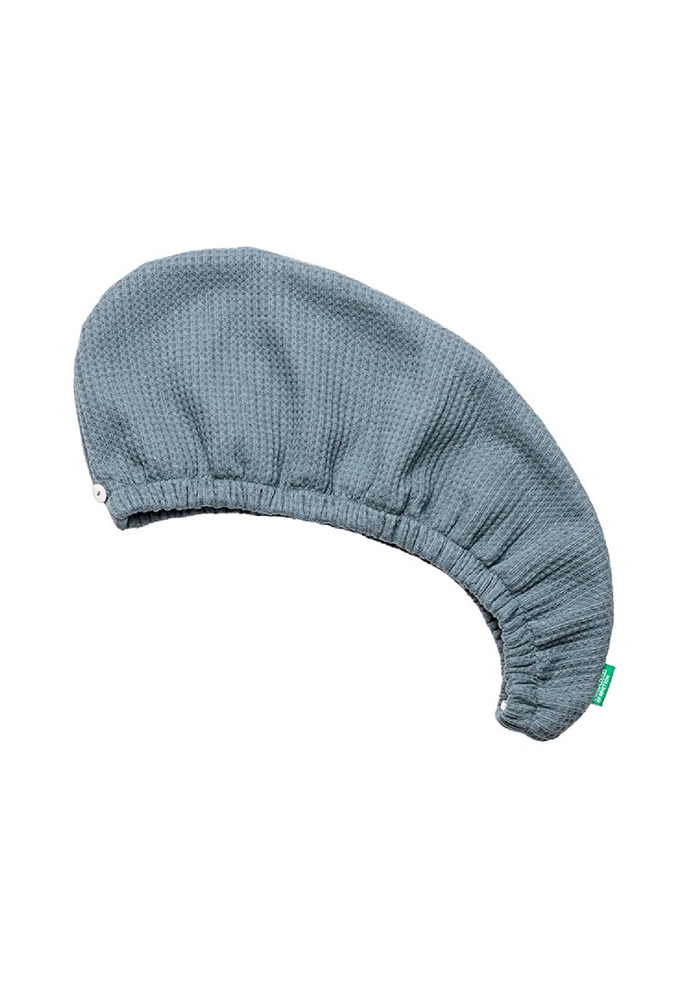 Cappuccio da doccia in tessuto leggero blu chiaro con una fascia elastica e una piccola etichetta verde su sfondo bianco.
