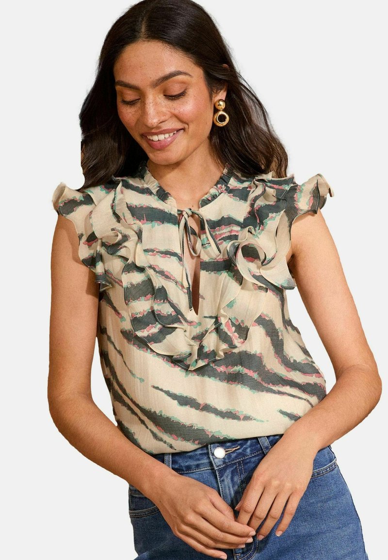 Blusa senza maniche in beige chiaro con scollatura arricciata, motivo a righe verdi e rosa e dettaglio con fiocco davanti. Tessuto morbido.