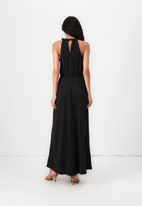 Vestido maxi preto com decote halter, cintura elástica e detalhe nas costas abertas. Tecido suave com uma silhueta reta e fluida.