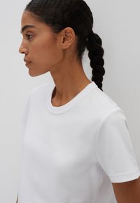 Weißes T-Shirt mit kurzen Ärmeln und Rundhalsausschnitt, aus glattem Baumwollstoff gefertigt. Verfügt über saubere Nähte und einen lockeren Schnitt.