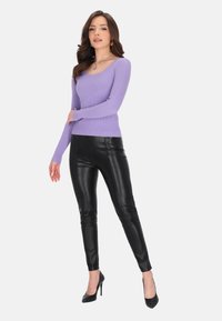 Lavendelfarbener, gerippter Strickpullover mit langen Ärmeln, kombiniert mit eng anliegenden schwarzen, kunstledernen Hosen und schwarzen High Heels.