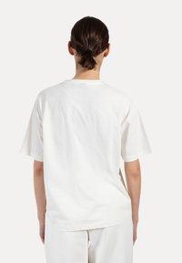 Biała bawełniana koszulka z luźnym krojem, krótkimi rękawami i okrągłym dekoltem, z gładkim tyłem i minimalistycznym wzornictwem.