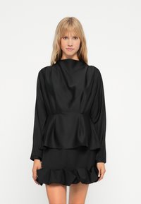 Černé saténové šaty s vysokým výstřihem, dlouhými rukávy, peplum pasem a volánkovým lemem. Hladká textura s elegantním vzhledem.