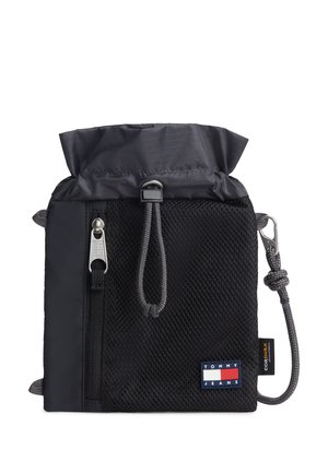 Czarna sakiewka Tommy Jeans z troczkiem, z przednią kieszenią z siateczki, zamkiem błyskawicznym, szarym paskiem sznurkowym z metalowym klipsem oraz etykietą z tkaniny Cordura.