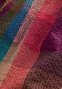 Kleurrijke geweven stof met gestructureerde, verhoogde stippenpatronen in strepen van groen, blauw, beige, rood, paars en roze.