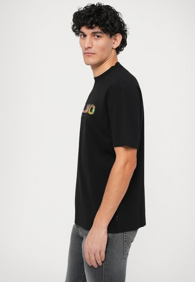 Svart t-shirt med kort ärm och rund halsringning. Har en flerfärgad "MILANO"-grafik på bröstet. Mjuk bomullstyg, avslappnad passform.