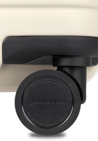 Hartschalenkoffer in Creme mit einem schwarzen Rad. Er hat eine glatte Oberfläche und ein rundes Rad mit eingeprägtem Branding.