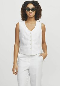 Biała bezrękawnik o dekolcie w kształcie litery V i pięcioma guzikami, z dwoma bocznymi kieszeniami i dopasowanym krojem. Połączony z pasującymi spodniami.