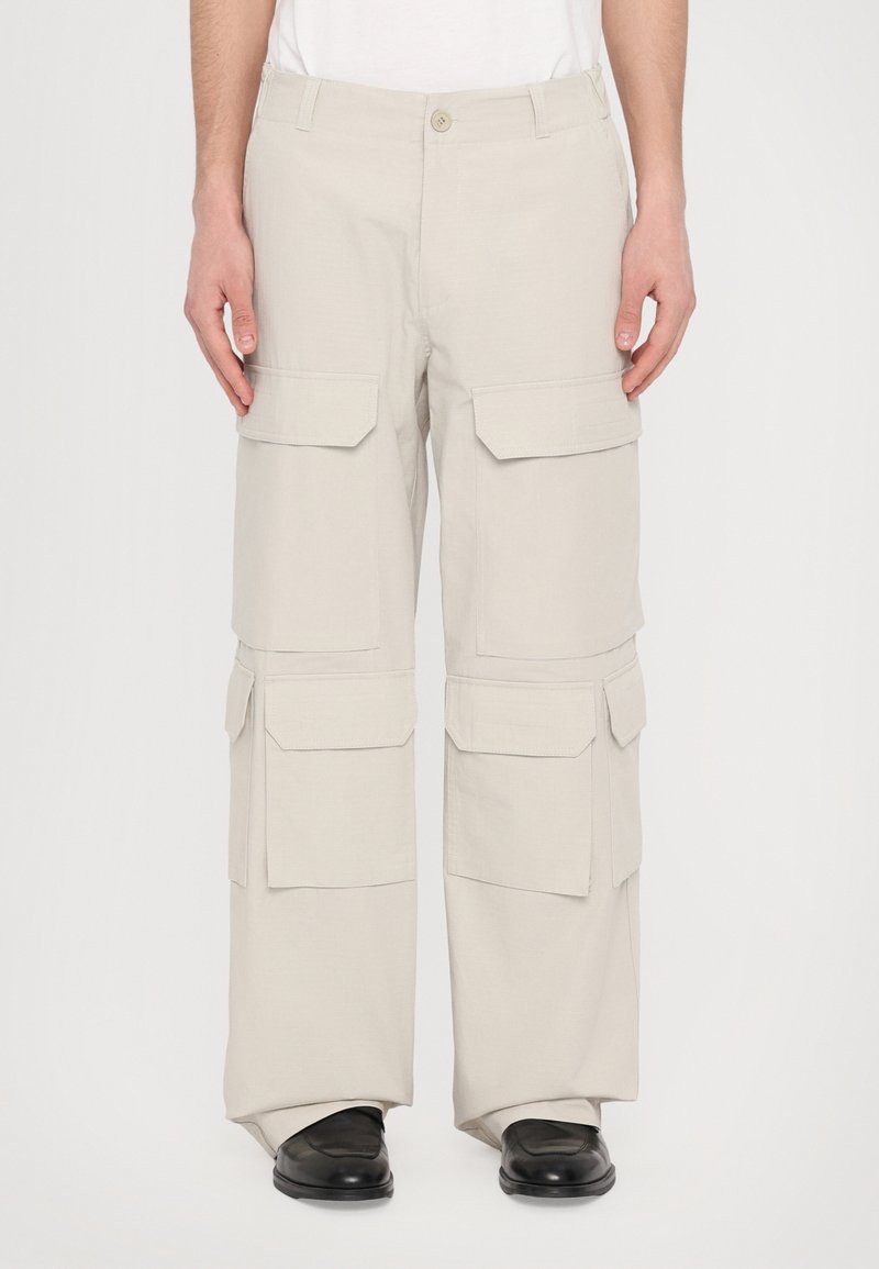 Pantaloni cargo bej din material ușor, cu multiple buzunare mari cu clapă, design drept pe picior și închidere cu un singur buton.
