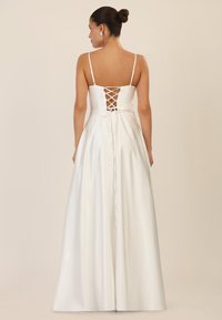 Weißes Satin-Kleid mit verstellbarem Schnürung im Rücken, dünnen Trägern und einem fließenden Rockdesign. Glatte Textur mit einem dezenten Glanz.