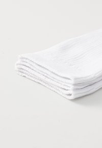 Białe skarpetki bawełniane starannie ułożone, z prążkowanym wzorem i wzmocnionym palcem. Materiał wydaje się miękki i ma czysty, klasyczny wygląd.