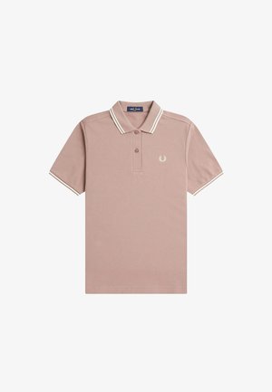 Polo en tissu rose doux, avec un col à rayures blanches, trois boutons et un petit logo brodé sur la poitrine gauche.
