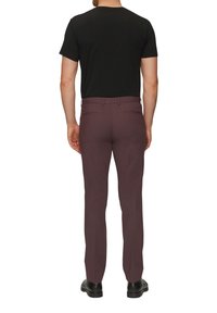 Herenoutfit met een zwart t-shirt en slim fit bordeauxrode broek. De broek heeft een soepele textuur en is voorzien van achterzakken en riemlussen.