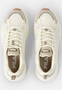 Białe siatkowe sneakersy z beżowymi akcentami, okrągły czubek, wyściełany kołnierz i teksturowana podeszwa. Posiadają logo na języku i pięcie.