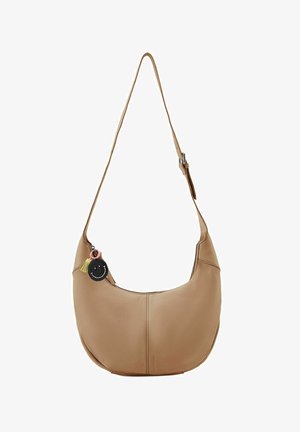 Beige leren schoudertas met een asymmetrische vorm, voorzien van een decoratieve smiley sleutelhanger en een enkele verstelbare schouderband.