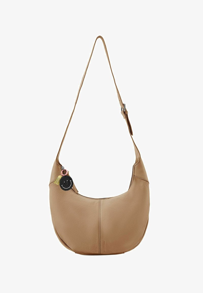 Beige Leder Schultertasche mit asymmetrischer Form, ausgestattet mit einem dekorativen Smiley-Schlüsselanhänger und einem einzelnen verstellbaren Schultergurt.