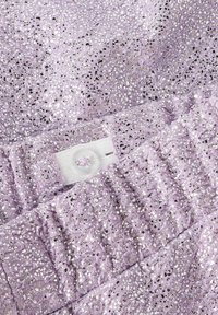 Tissu lavande avec des sequins brillants, présentant un motif texturé et une fermeture à bouton, affichant une surface douce et réfléchissante.