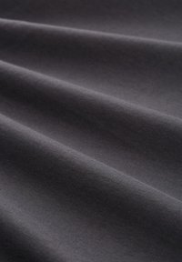 Tejido gris oscuro con una textura suave, que muestra suaves y sutiles pliegues y un patrón uniforme. Iluminado para resaltar la superficie del tejido.