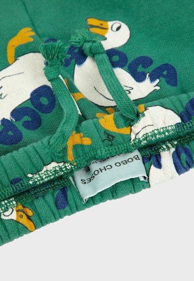 Green cotton shorts with a duck print. Features elastic waistband with drawstrings, textile fringing, and a label on the interior.