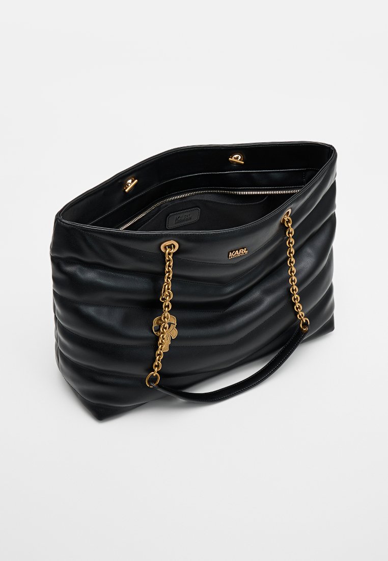Bolso tote de cuero negro con diseño acolchado, detalles en cadena dorada, dos asas y un bolsillo interior con cremallera.