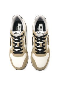 Zapatillas beige y blancas con un acabado texturizado, que presentan cordones y un logotipo negros, forma redondeada y una suela acolchada para mayor comodidad.