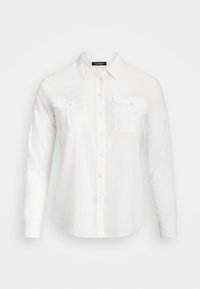 Vit skjorta med knappar i slät tyg, med krage, långa ärmar och två fickor med lock fram. Klassisk design, skräddarsydd passform.