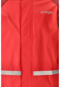 Chaqueta impermeable roja con franjas reflectantes plateadas. Presenta una textura suave y una costura central. Logo de la marca "ZIGZAG" exhibido en el pecho.