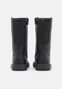 Bottines noires avec une finition en cuir lisse, présentant des panneaux élastiques sur les côtés, un petit talon et des fermetures éclair double à l'arrière.
